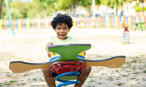 Preview: Latin boy with afro hair playing happily in a playground