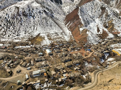 Preview: Rustic village in a snowy, brown valley beneath steep mountain slopes