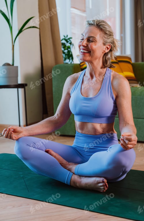 Preview: Senior woman practicing yoga meditation at home on a mat