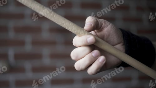 Preview: Close up of man hand with black fabric bracelet on his wrist holding drumstick and rotating it with