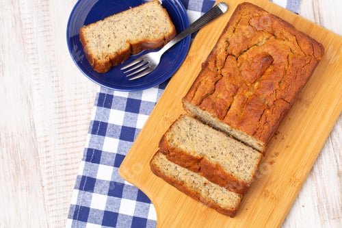Preview: Banana Bread Made Gluten Free On Wooden Cutting Board With Slice On Blue Plate