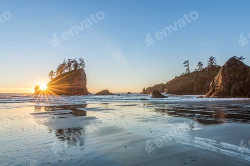 Preview: Sun rising over rock formations on beach