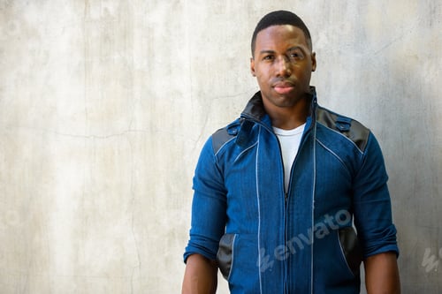 Preview: Portrait of young handsome African man against concrete wall