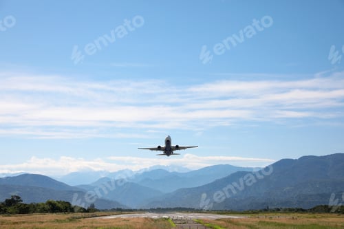 Preview: Modern white airplane landing on runway near mountains