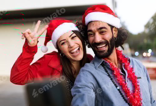 Preview: Smiling friends wearing santa hats take selfie. Christmas time.