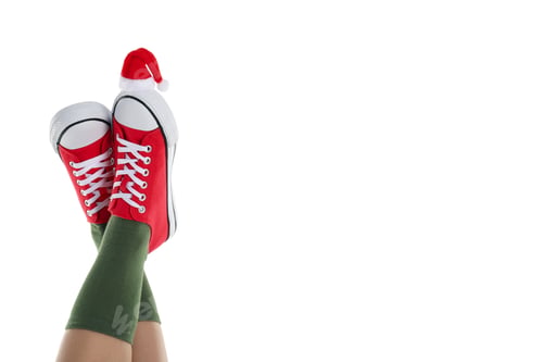 Preview: Female legs in sneakers with Santa hat isolated on white background