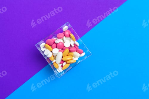 Preview: A pile of multicolored pills on blue background. Top view