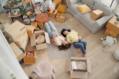 Preview: Asian girl friends lying down on the floor enjoy talking about decorating room at the new home