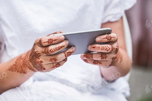 Preview: Woman with henna tattoo on hands using smartphone