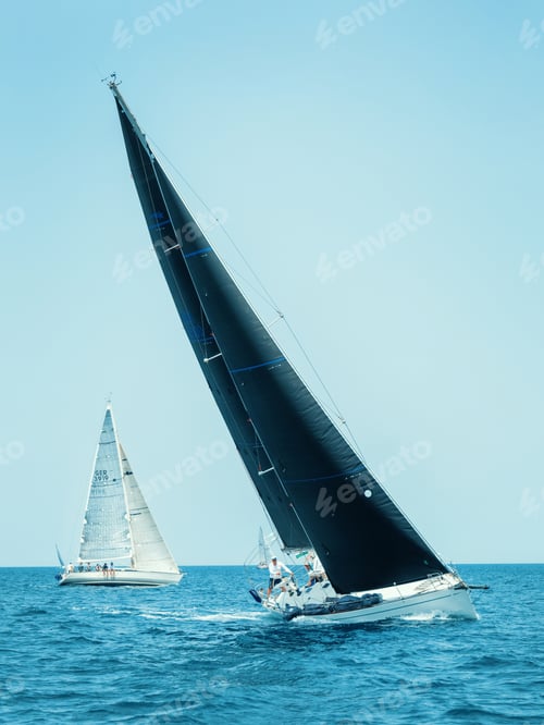 Preview: Sailboats races in regatta near Brindisi under blue sky. Crew members working together on deck