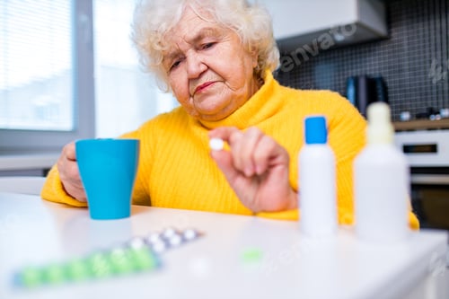 Preview: Senior Woman Taking Medication in Home Kitchen