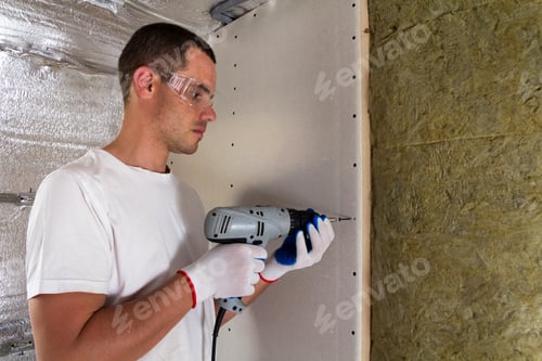 Preview: Worker in goggles with screwdriver working on insulation