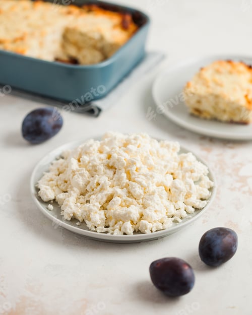 Preview: Plate of crumbly cottage cheese, plums, with a homemade casserole in the back.