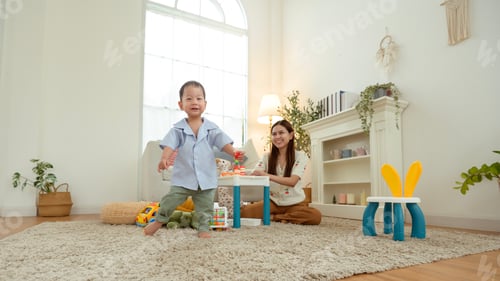 Preview: Boy Takes His First Steps at Home While Holding His Mother's Hand in a Warm Living Room Setting