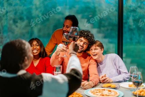 Preview: Friends toasting red wine at dinner party celebrating with pizza and wine