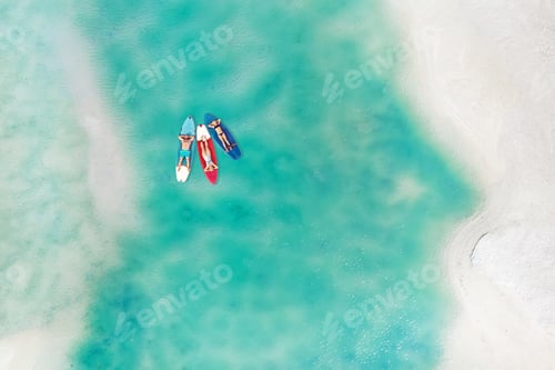 Preview: The family is resting lying on Sup boards in the turquoise sea. Three people ride sup boards in the