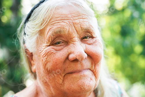 Preview: close up portrait of a senior woman in a garden. Very old lady of eighty years old outdoor in summer