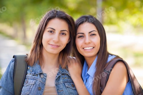 Vista previa: Retrato de una hermana gemela de raza mixta joven con mochilas en el exterior.