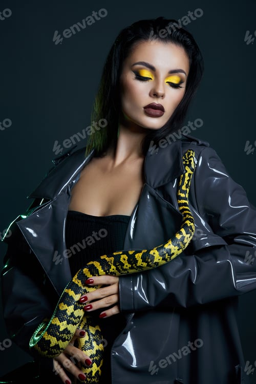 Preview: Beauty woman python yellow snake around her neck on latex shiny raincoat. Yellow snake