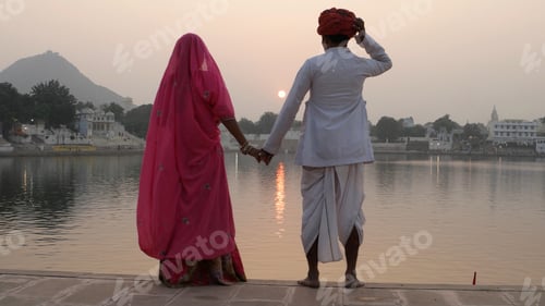 Preview: Indian couple in traditional outfits looking at the Ganges during sunset.