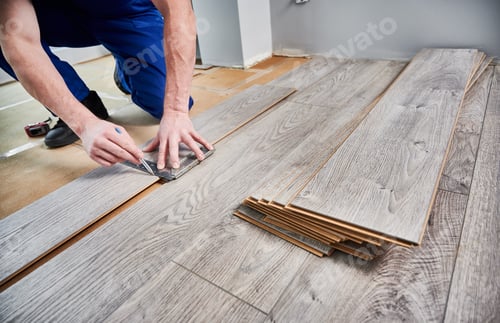 Preview: Male worker hands drawing line on laminate wood plank.