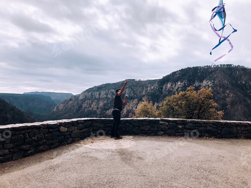 Preview: Man Flying Kite Amidst Mountain Vista