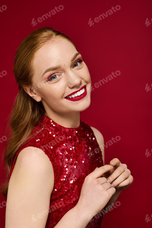 Preview: Captivating young woman shining brightly in a vibrant red outfit against a bold backdrop