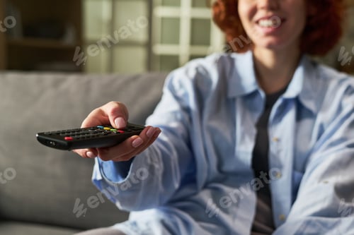 Preview: Young Adult Woman Smiling While Holding Television Remote Control