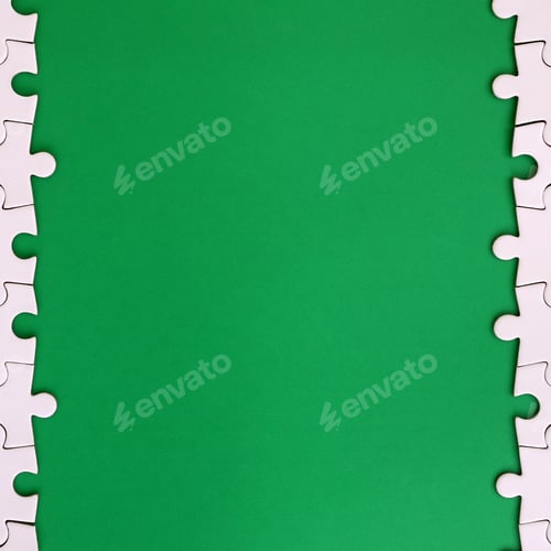 Preview: Fragment of a folded white jigsaw puzzle on the background of a green plastic surface