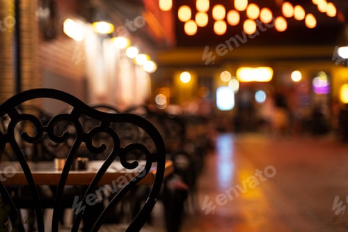 Preview: black chairs with tables on terrace on a illuminated street