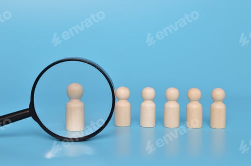 Preview: Talent sourcing concept. Wooden doll figures and magnifying glass.