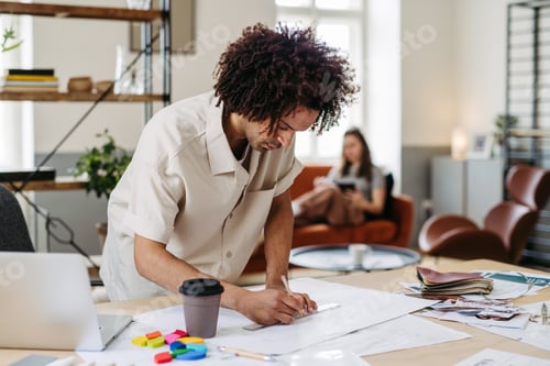 Preview: Young multiracial man drawing something in designers studio.