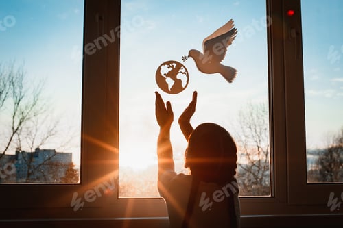 Preview: child stretches his hands sunlight sunset outside window flying dove world with branch forces globe