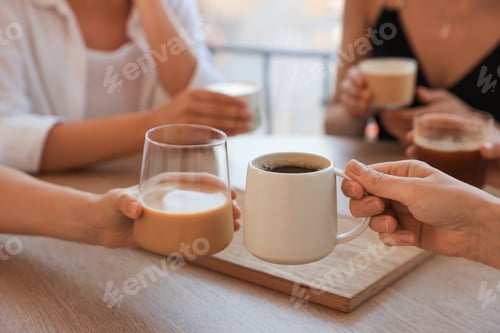 Preview: Friends drinking coffee at wooden table in cafe, closeup