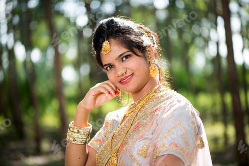 Preview: Beautiful Indian bride in traditional wedding dress at outdoor.