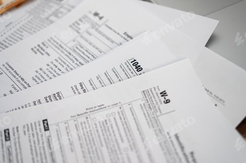 Preview: Tabletop cluttered with diverse tax forms signifying annual tax preparation ritual