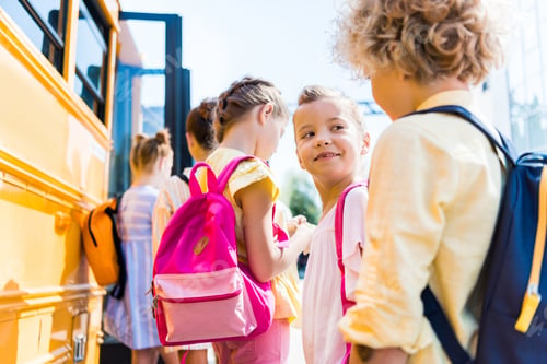 Preview: close-up shot of group of adorable schoolchildren standing near school bus
