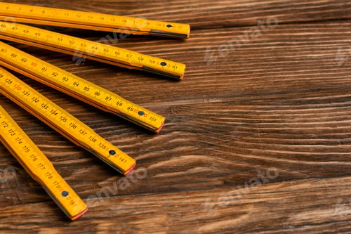 Preview: yellow folding ruler on wooden surface, labor day concept