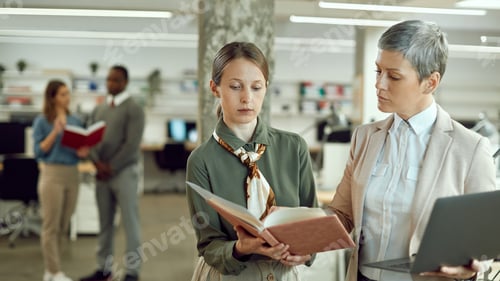 Preview: Businesswoman going through reports with female executive manager in the office.