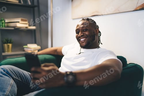 Preview: Smiling Man Relaxing on Green Couch with Phone