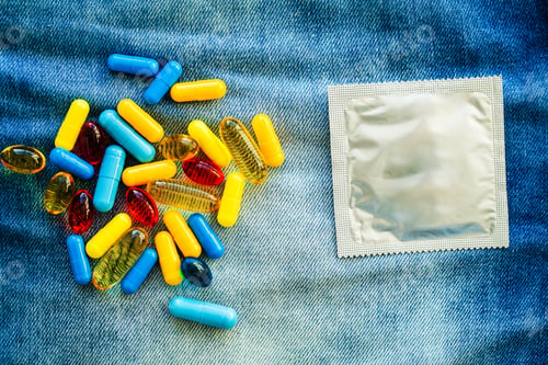 Preview: Medical potency pills and condom on jeans.