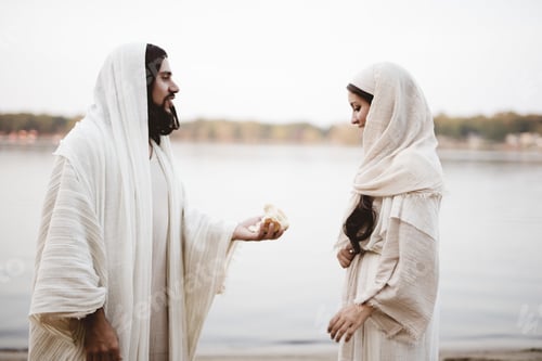 Preview: Shallow focus shot of Jesus Christ offering peace of bread to a female wearing a biblical gown