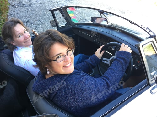 Preview: Two happy women in a classic 1973 sports car with the hood down.