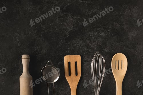 Preview: flat lay with various wooden and steel kitchen utensils isolated on black surface