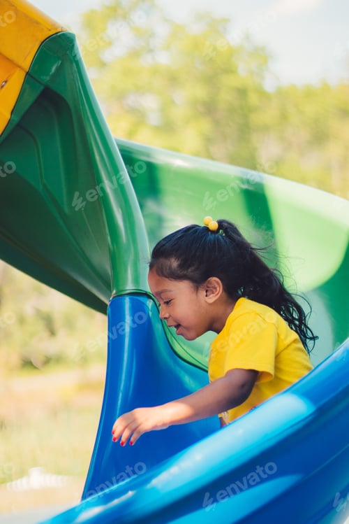 Preview: A mixed race little girl sliding down a twirly slide at the park