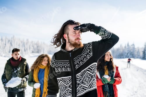 Preview: Group of young friends on a walk outdoors in snow in winter forest, having fun