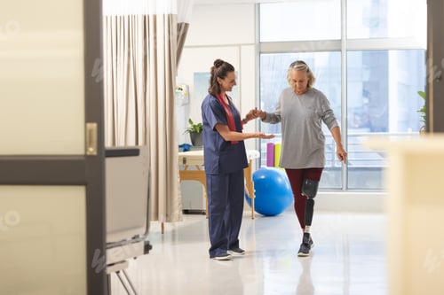 Preview: Caucasian female physiotherapist and senior woman with artificial leg walking