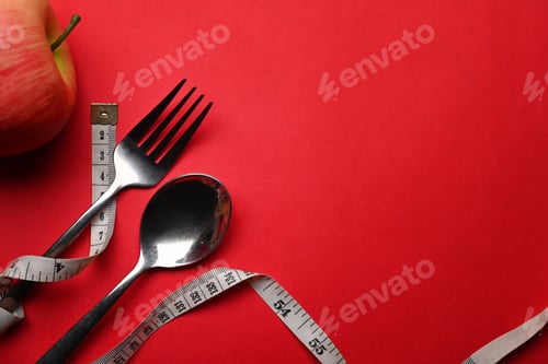Preview: Measure tape, spoon fork and apple on red background with copy space for text.