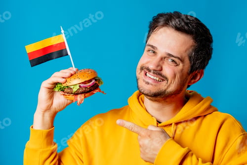 Preview: hungry guy with burger and german flag on blue background