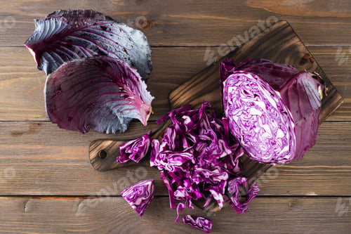 Preview: Sliced head of red cabbage on a cutting board on a wooden table. Top view